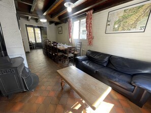 Una zona pranzo con un tavolo e sedie in legno, un divano in pelle nera e una mappa appesa al muro.