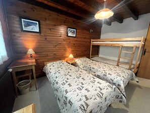 Una camera in stile baita con due letti a castello, un piccolo tavolo con una lampada e due quadri appesi al muro.