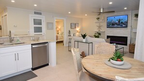 A modern kitchen with white cabinets, a dishwasher, and a dining area with a wooden table and chairs. - Stay at the Best Condo in the Complex, 5 floor with privacy and best water view! (Marco Island)