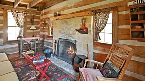 A cozy log cabin interior with a stone fireplace, wooden furniture, and a rustic decor. - Ab Butler - Cumberland River 1 Bedroom Cabin by RedAwning (Fredericksburg)