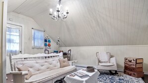 Een gezellige kamer met een witte bank, een klein tafeltje, een stoel en een kamerkleed met dessin.