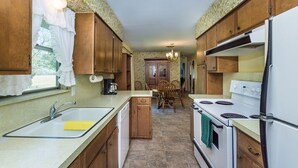 A compact kitchen with wooden cabinets, a white stove, and a sink. - Oma's Haus 2 Bedroom Home by RedAwning (Fredericksburg)