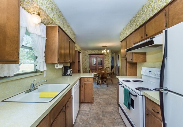A compact kitchen with wooden cabinets, a white stove, and a sink.