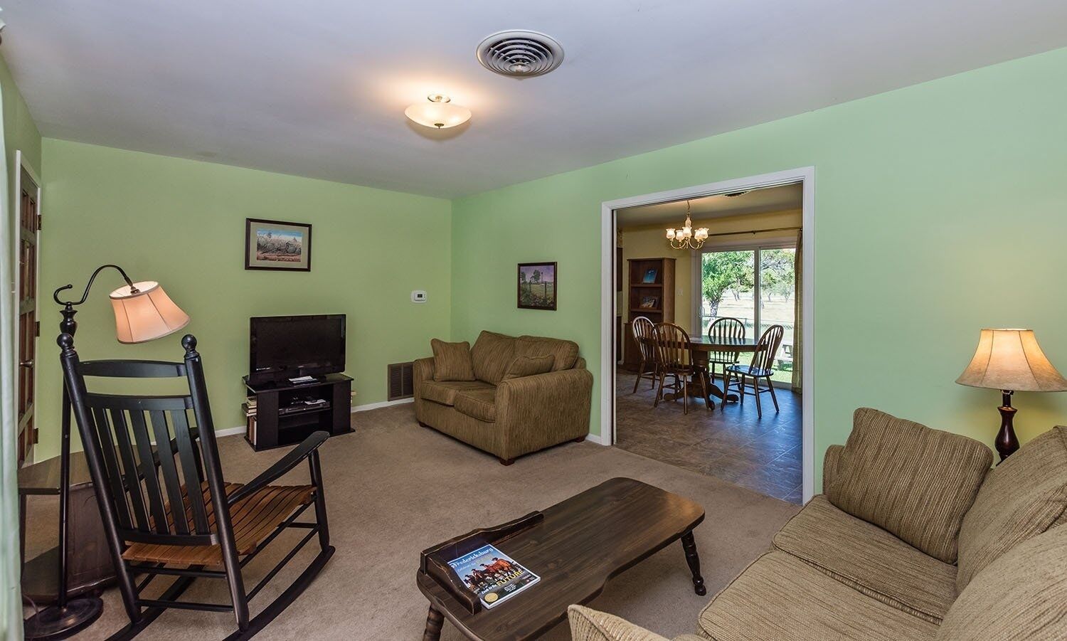 A living room with a television, sofa, and dining area.