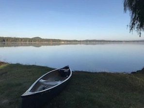 Enjoy a serene lakeside retreat with a canoe waiting to explore the surrounding hills.