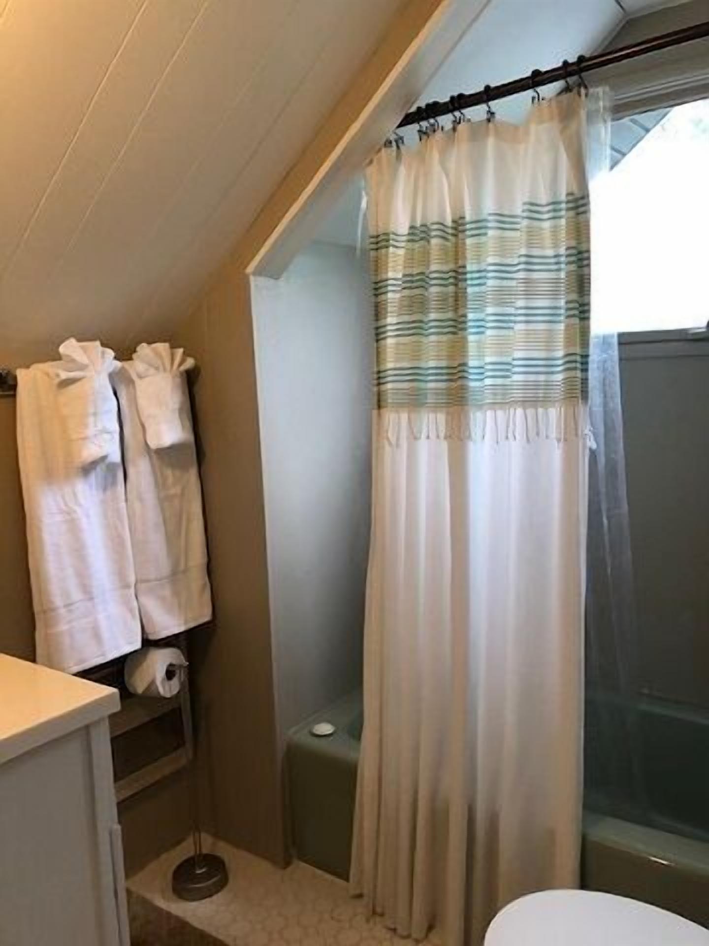 Une salle de bain avec un rideau de douche, un porte-serviettes avec des serviettes et des toilettes.