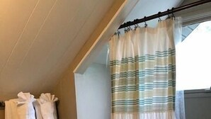 A bathroom with a shower curtain, a towel rack with towels, and a toilet. - Beautiful 5-bedroom cottage across from Bass Lake (Pentwater)