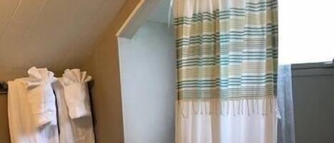 Une salle de bain avec un rideau de douche, un porte-serviettes avec des serviettes et des toilettes.