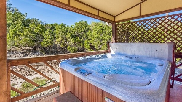 A hot tub with a wooden deck and a view of trees.