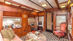 A cozy interior with a wooden panel design, a television, a bookshelf, and a comfortable seating area. - 1894 Private Pullman Palace Ca 1 Bedroom Apts by Redawning (Fredericksburg)