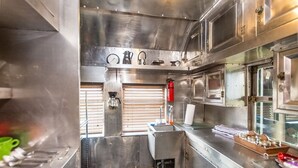 A stainless steel commercial kitchen with a sink, a fire extinguisher, and various kitchen utensils. - 1894 Private Pullman Palace Ca 1 Bedroom Apts by Redawning (Fredericksburg)