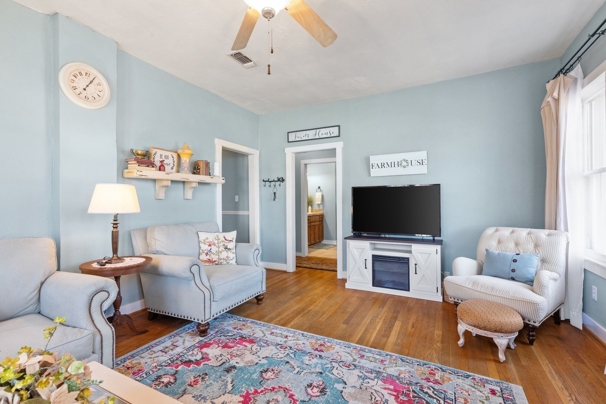 A living room with a TV, sofas, a rug, and a ceiling fan.