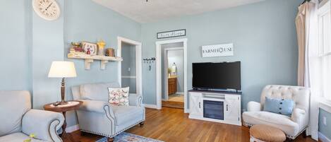 A living room with a TV, sofas, a rug, and a ceiling fan.
