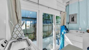 Ein Zimmer mit einer Schiebetür zum Garten, einer Küchenzeile inklusive Herd und einem Deckenventilator.