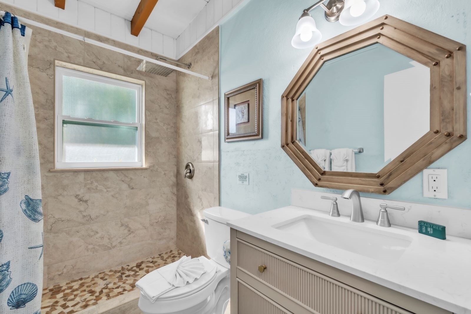 A bathroom with a shower, a sink, a toilet, and a large mirror.