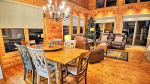 A wooden interior with a dining table, chairs, sofas, and a chandelier. - Sky High in West Jefferson, NC: Spacious 4BR cabin for 10 with stunning mountain views. (West Jefferson)