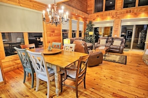 A wooden interior with a dining table, chairs, sofas, and a chandelier. - Sky High in West Jefferson, NC: Spacious 4BR cabin for 10 with stunning mountain views. (West Jefferson)