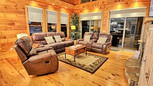 A wooden interior with a leather sofa set, a coffee table, and a Christmas tree. - Sky High in West Jefferson, NC: Spacious 4BR cabin for 10 with stunning mountain views. (West Jefferson)