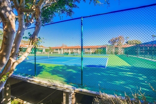 Enjoy a game of tennis on this well-maintained court surrounded by a green fence.