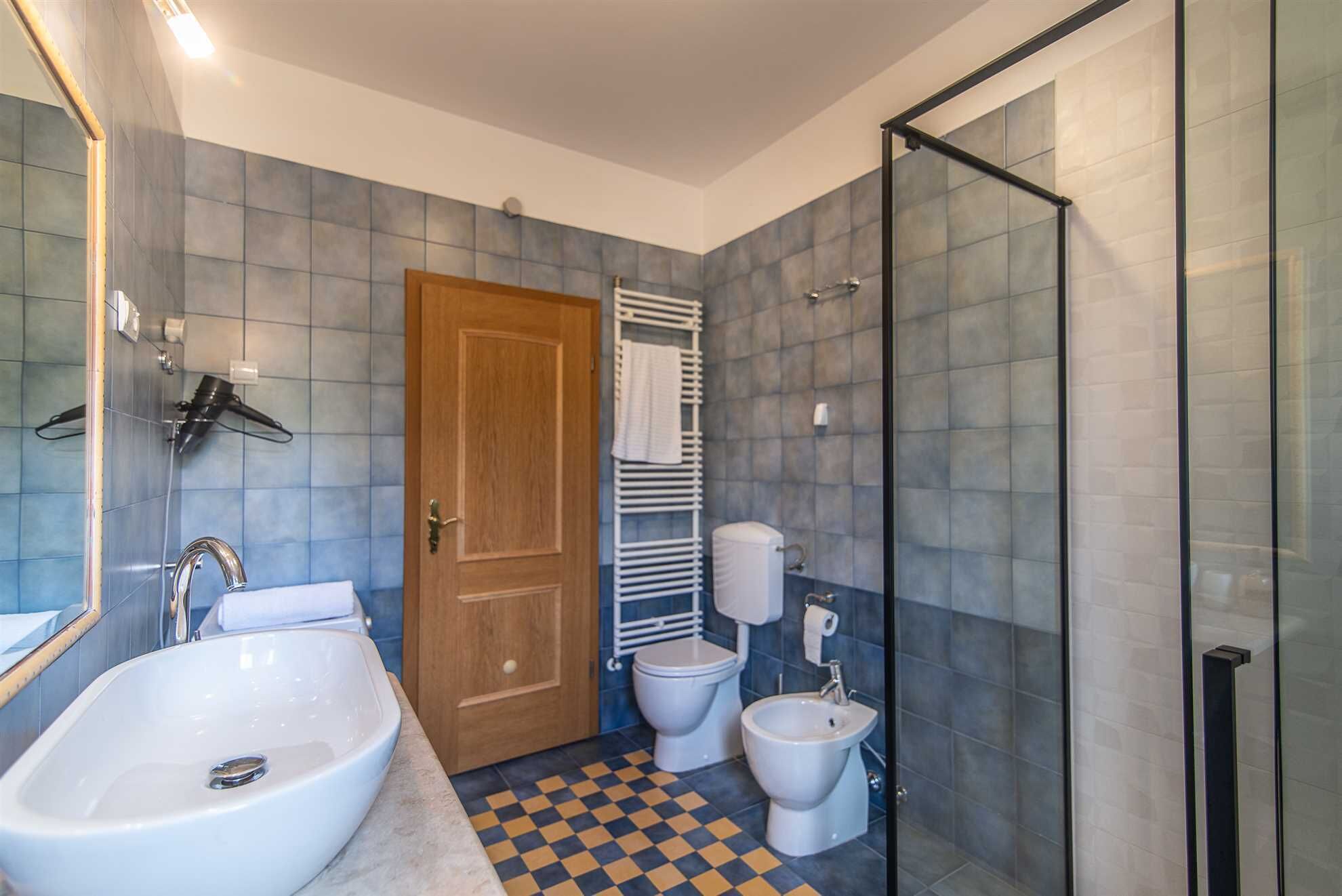 A bathroom with a sink, toilet, bidet, and a shower area.