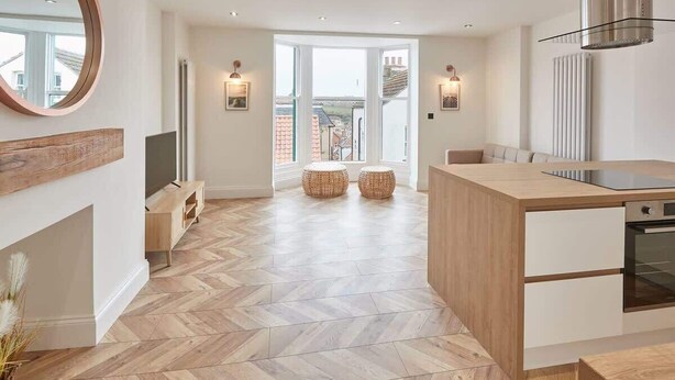 A modern kitchen with a herringbone floor, wooden island, and built-in oven. - Host & Stay | Abbey Hus (Whitby)