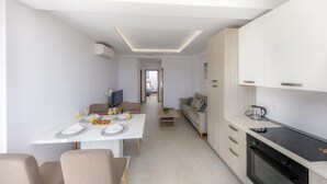 A modern kitchen with a black stove, white cabinets, and a dining area with a table set for two.