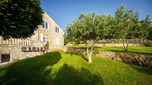 A stone building with a well-maintained lawn and a tree in the foreground. - Apartments Mi&ni (Konavle)