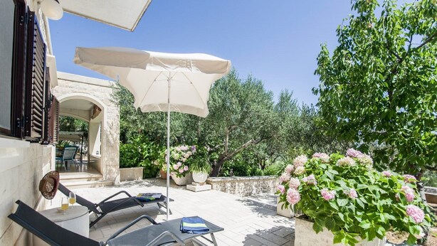 An outdoor patio with two lounge chairs, a table, and a large umbrella. - Holiday Home Villa Spilla (Selca)