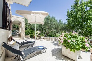 An outdoor patio with two lounge chairs, a table, and a large umbrella.