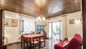 A dining area with a wooden ceiling, a TV, and a red sofa. - Holiday Home Villa Spilla (Selca)