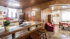 A kitchen with wooden paneling, a stainless steel refrigerator, a dining table with chairs, and a red armchair. - Holiday Home Villa Spilla (Selca)