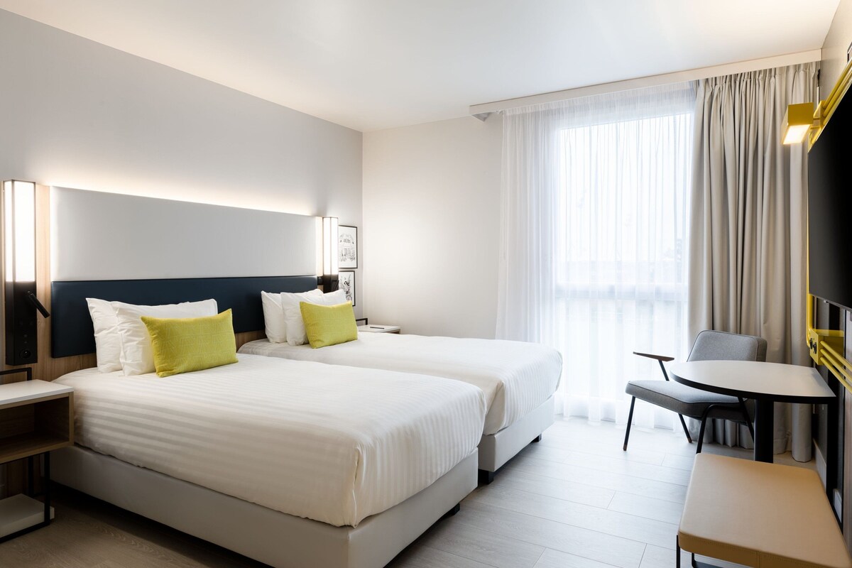 Una habitación de hotel con dos camas, un escritorio y una silla.