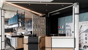 A modern kitchen with a central island, bar stools, and a decorative wall with architectural drawings. - Courtyard by Marriott Paris Creteil (Creteil)
