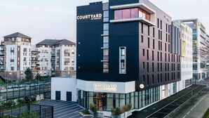 A modern hotel with a 'Courtyard by Marriott' sign, a 'Kitchen & Bar' sign, and a parking lot. - Courtyard by Marriott Paris Creteil (Creteil)