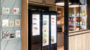 A modern kitchen with a built-in refrigerator, wooden cabinets, and a hanging light fixture. - Courtyard by Marriott Paris Creteil (Creteil)