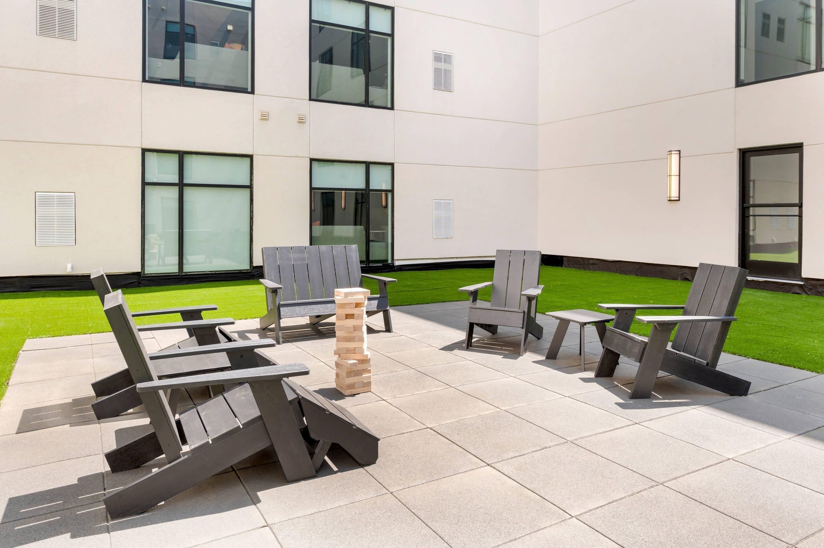 Un espace extérieur aménagé avec des chaises Adirondack et une tour faite de blocs de bois.