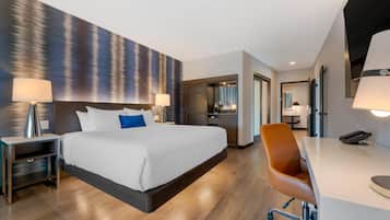 Una habitación de hotel moderna con una cama grande, mesitas de noche, un escritorio y una silla.