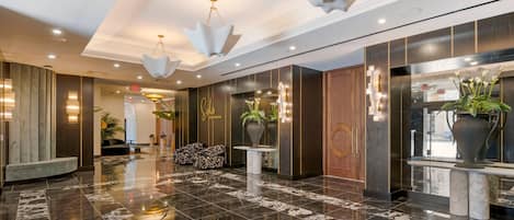 A modern lobby with marble flooring, contemporary lighting fixtures, and a reception desk.