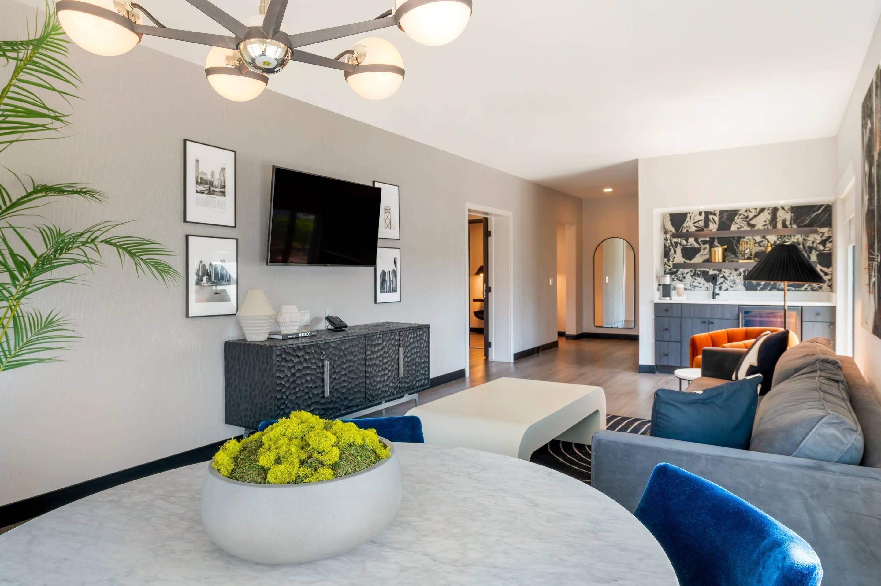 A modern living room with a round table, a sofa, and a TV mounted on the wall.