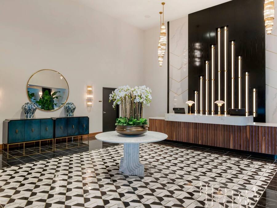 Een receptie met een incheckbalie, een ronde tafel met een bloempot, een decoratieve spiegel en een vloer met een patroon.