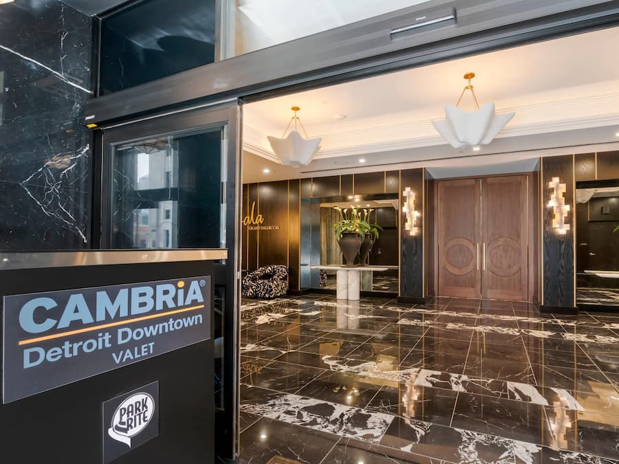 A lobby with a marble floor, a reception desk, and a sign for CAMBRIA Detroit Downtown Valet.