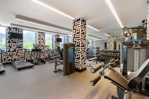 Une salle de sport moderne équipée de tapis de course, d’appareils de musculation et de poids libres.