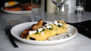 A plate of food with an omelet, potatoes, and cheese on a table.