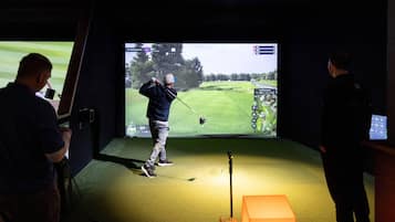 A golf simulation setup with a large screen, a golf club, and a target.