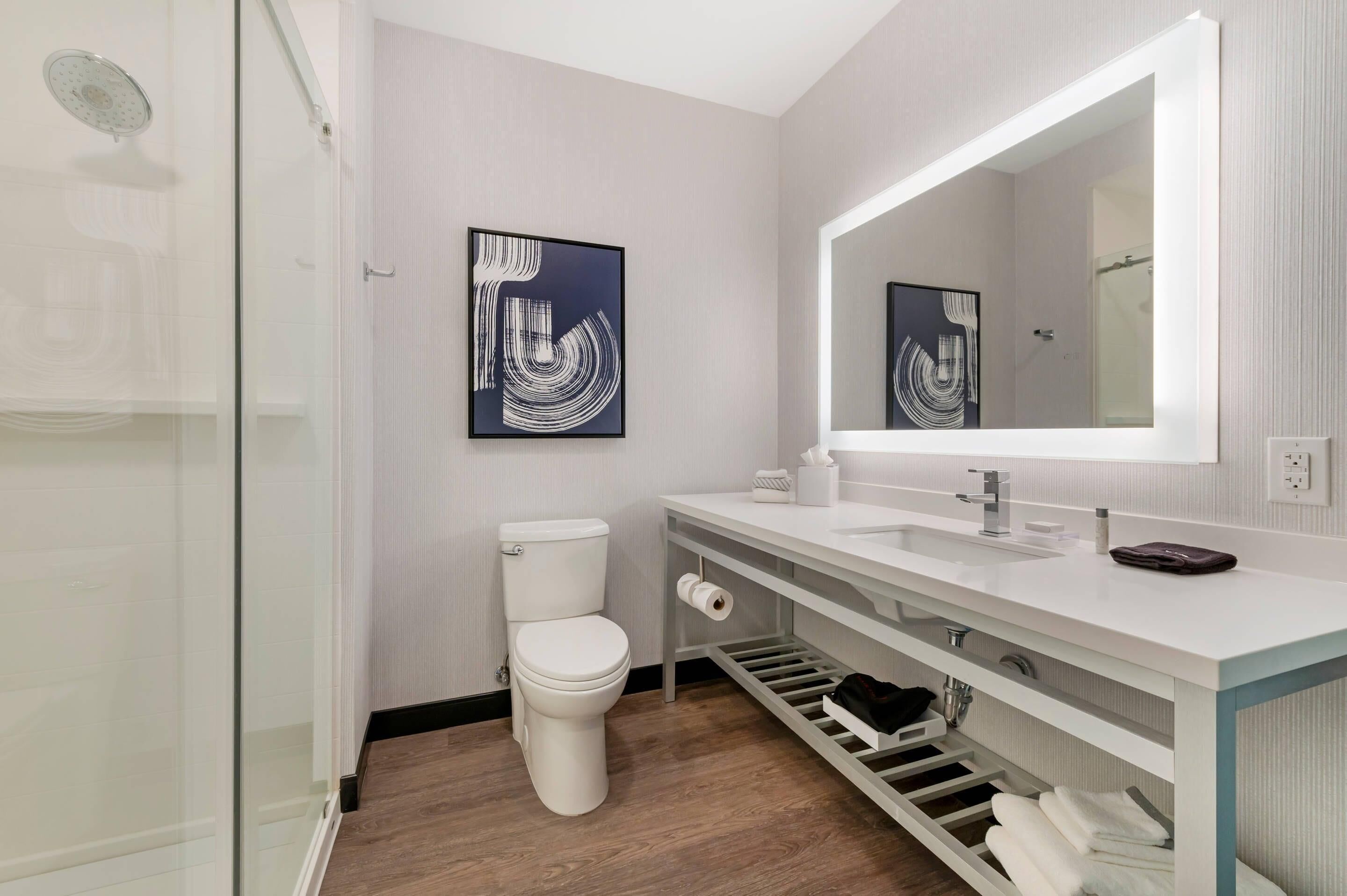 Un baño moderno con inodoro, lavamanos y ducha.