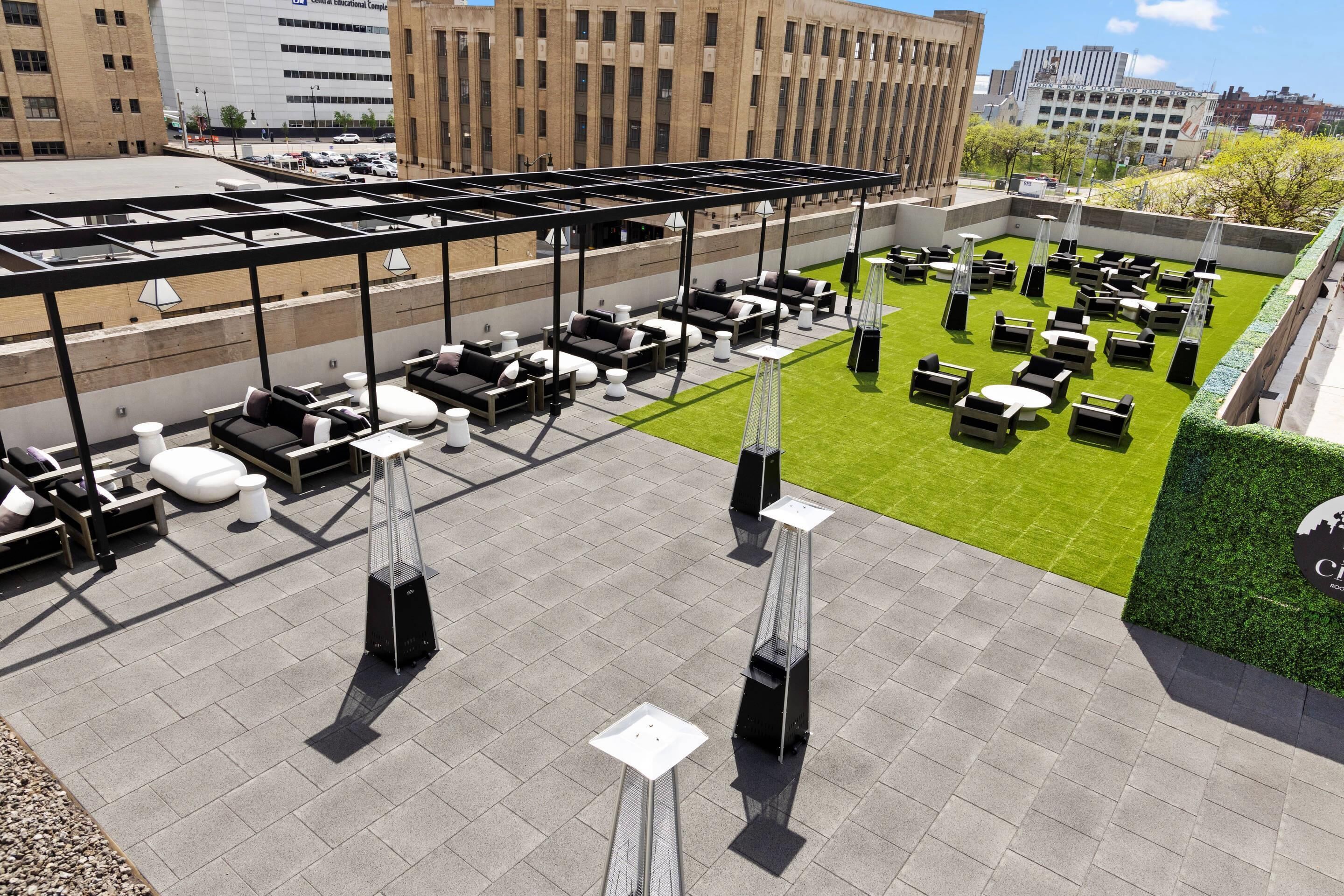 A rooftop terrace with outdoor seating and a green lawn area.