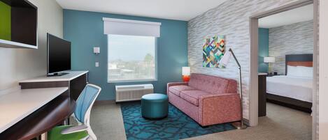 A hotel room with a desk, chair, sofa, and bed.