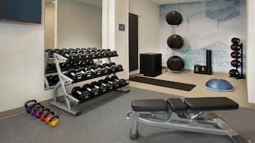 A gym with dumbbells, kettlebells, a bench, and exercise balls.