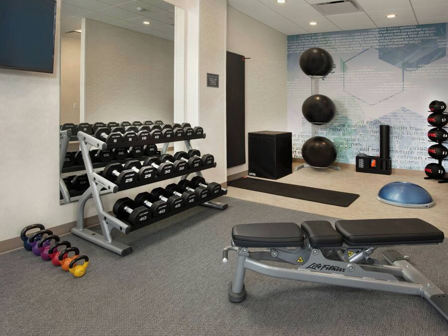 A gym with dumbbells, kettlebells, a bench, and exercise balls.
