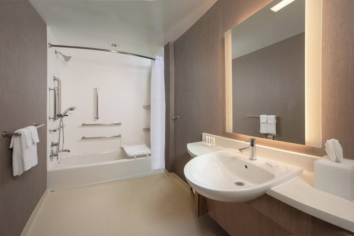 A modern bathroom with a bathtub, a sink, and a large mirror.